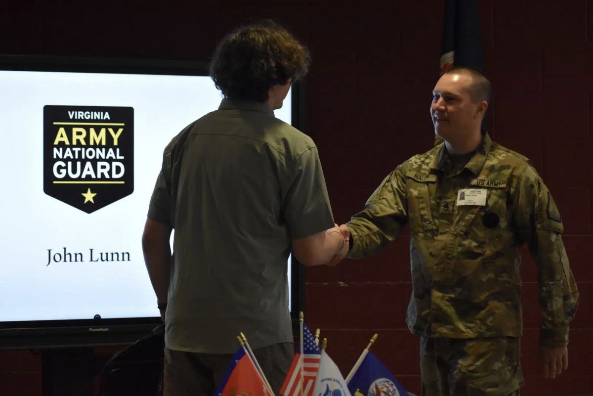 On May 2, seniors enlisting for the military gathered in the cafeteria to sign certificates and be recognized for their commitment to the military. Staff Sergeant Ryan Haley shakes senior John Lunn's hand. Haley has been Lunn’s sponsor for the Army National Guard for over a year since he first came to Rock Ridge during a lunch presentation and met Lunn. 
